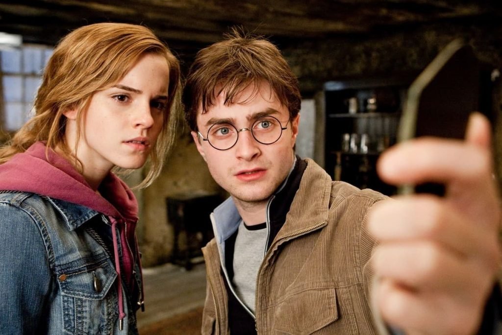 Dos personajes, Hermione y Harry Potter, observan juntos un objeto, mostrando una conexión intensa que muchos fans interpretan como un shipp dentro de la saga. Imagen de Warner Bros. Pictures